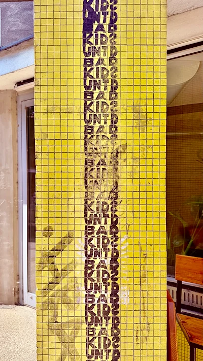 Yellow Tiled Column with Repeating Street Art Text