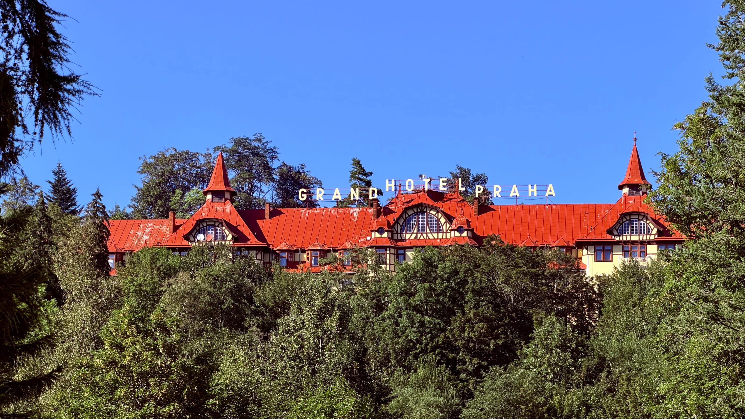 El Grand Hotel Praha, de tejado rojo, asomando por encima del bosque